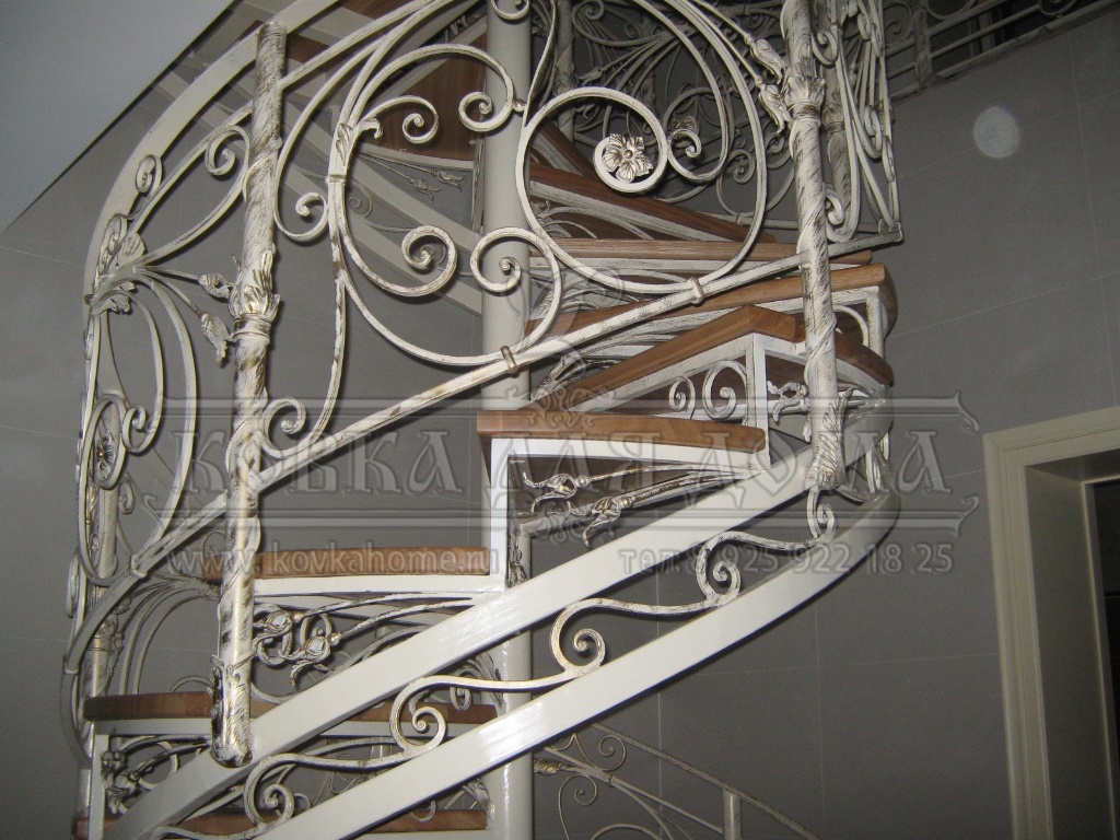 Винтовая каркасная кованая лестница с кованым декором и деревянными ступенями. 