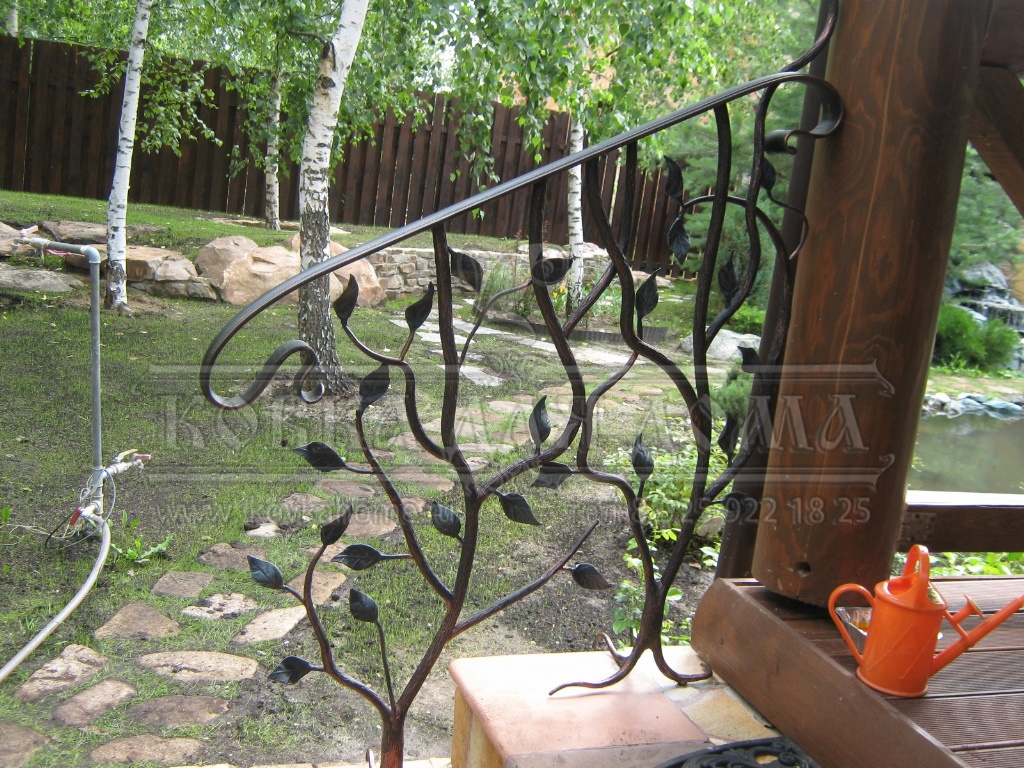 Кованые перила для ступенек крыльца в виде дерева с декоративными коваными «корнями» и металлическим поручнем.